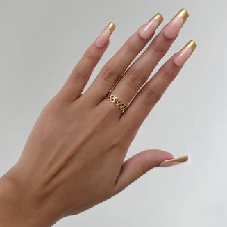 model wearing Hallie Ring features a striking gold plated band with a Celtic-inspired design, adorned with a classic love knot from Prya