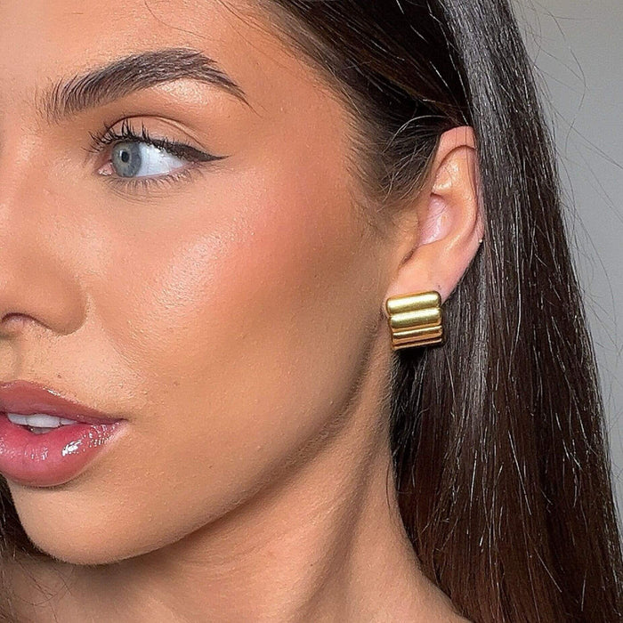 model wearing ribbed statement earrings in gold from prya