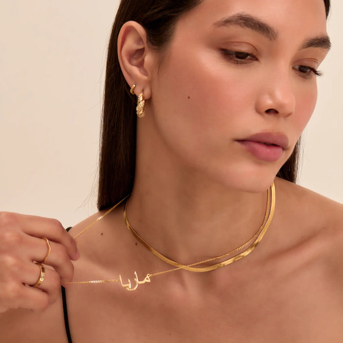 model wearing personalised arabic name necklace, herringbone necklace and hoop earrings in gold from prya
