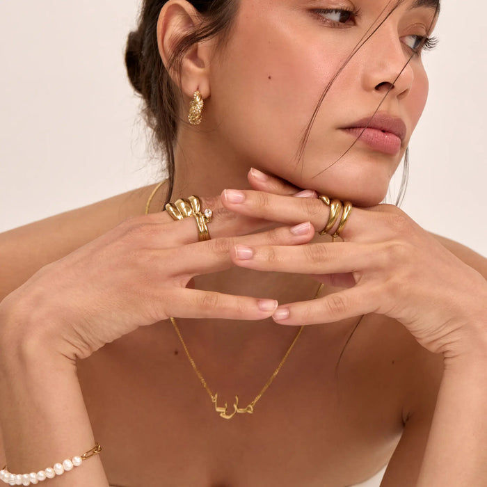 model wearing personalised arabic name necklace and chunky rings in gold from prya