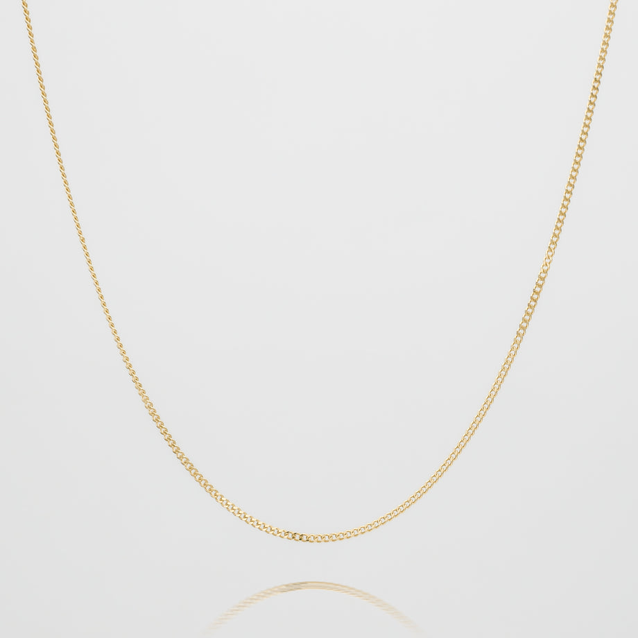 Gold curb chain necklace on white background.