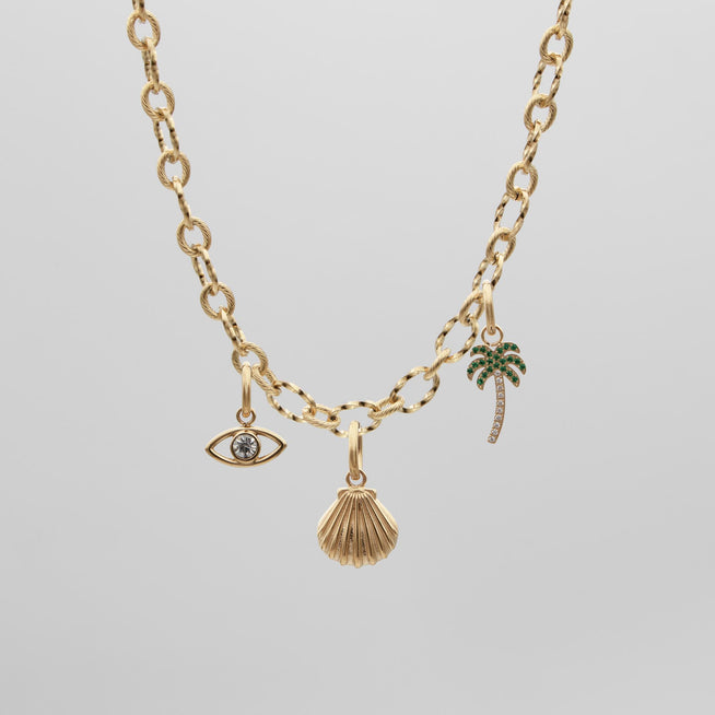 gold charm necklace with evil eye, seashell and palm tree charm from prya