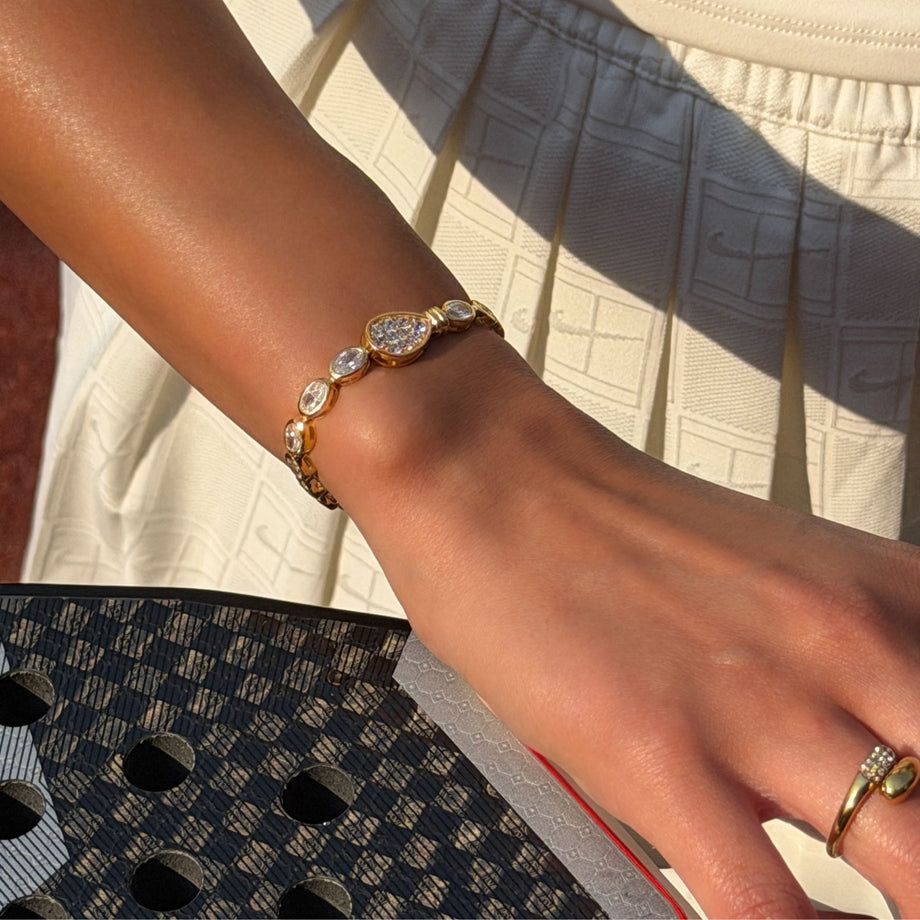 model wearingluxury padel bracelet in 18k gold vermeil Oval stones and pavé padel racket charm.