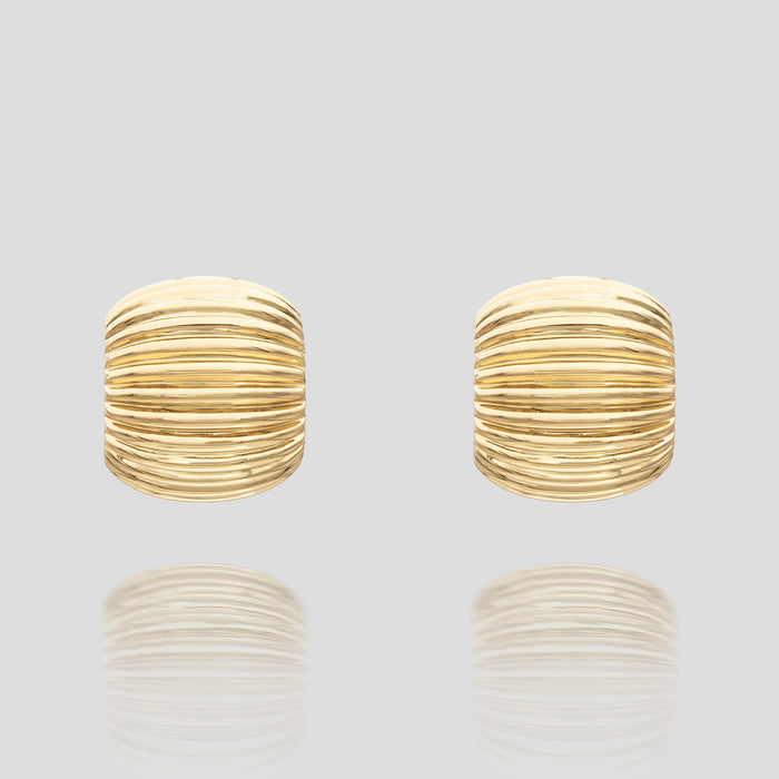 Gold ribbed stud earrings on grey background.