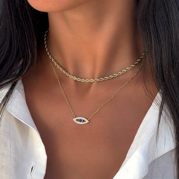 model wearing  gold evil eye necklace with  paved cz stones and blue stone centre