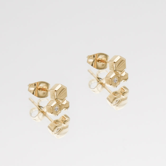 Gold hexagonal stud earrings with small diamonds.