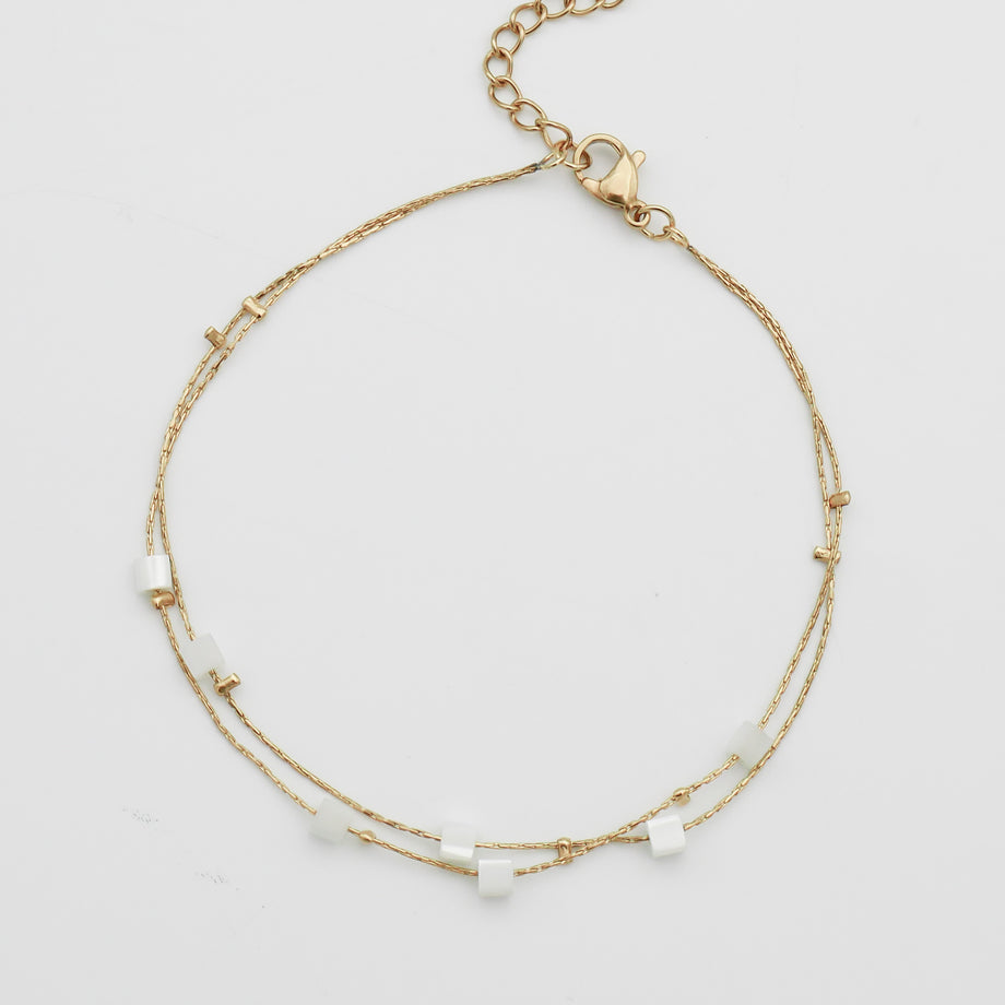 Delicate gold anklet with white beads.