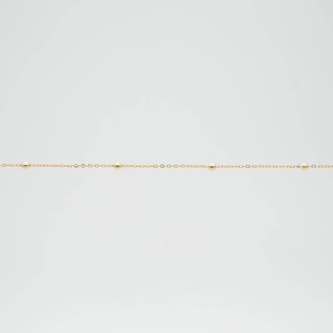 Delicate gold chain with small spheres.