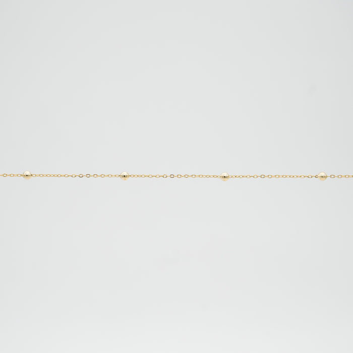 Delicate gold chain with small spheres.