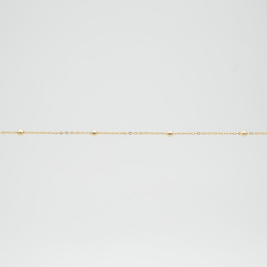 Delicate gold chain with small spheres.