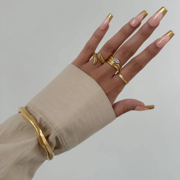 model wearing Thea Bangle, a minimalist textured 18k gold plated bracelet with a subtle wavy design from PRYA