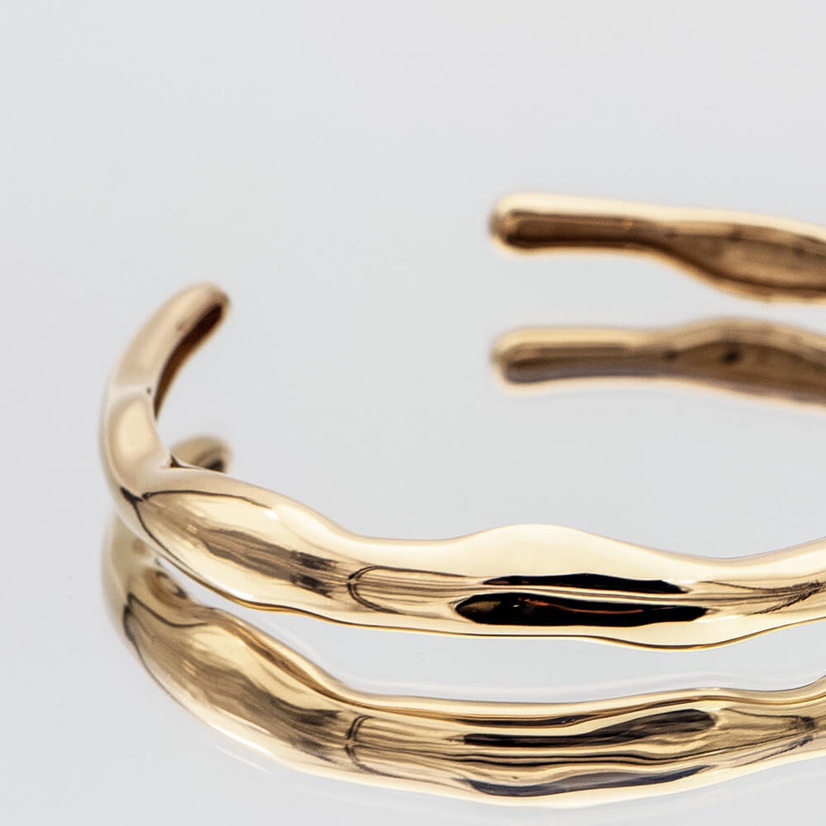 Thea Bangle, a minimalist textured 18k gold plated bracelet with a subtle wavy design from PRYA