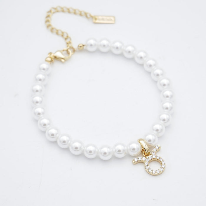 Gold charm pearl bracelet with adjustable clasp.