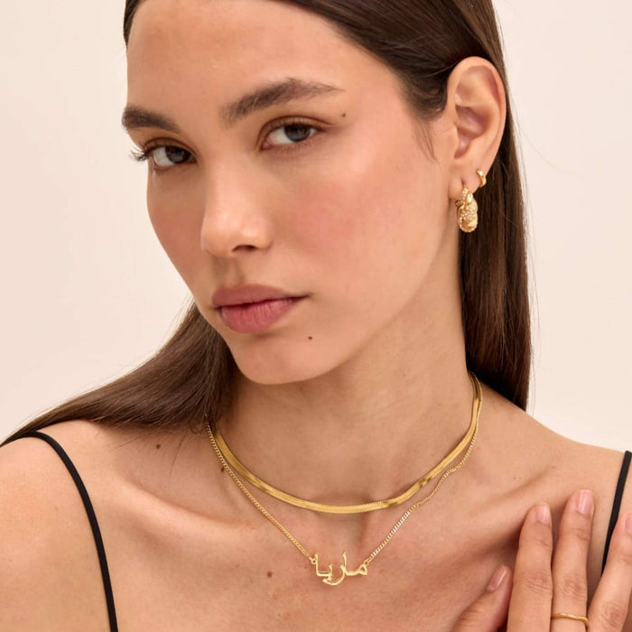 model wearing personalised arabic name necklace in gold layered with gold herringbone necklace from prya