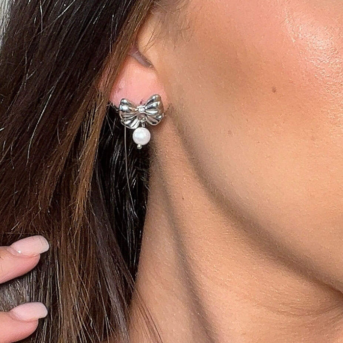 model wearing the bow pearl drop earring in silver from prya