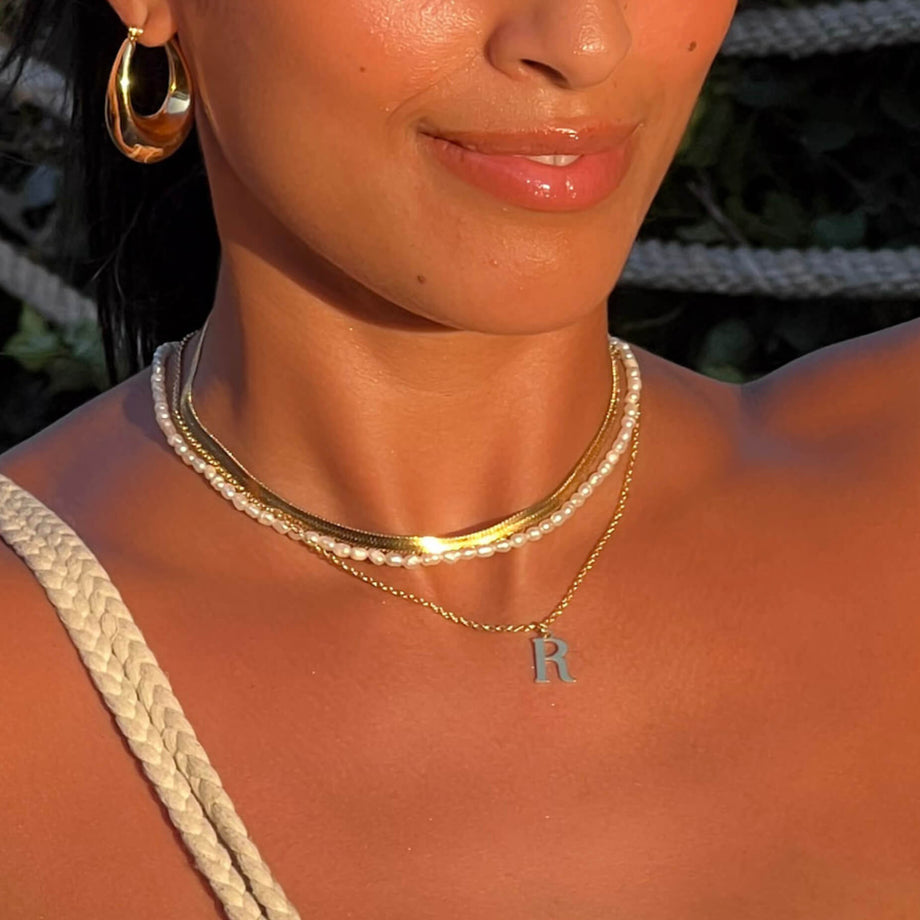 model wearing kayla initial necklace in letter R  in gold from prya 