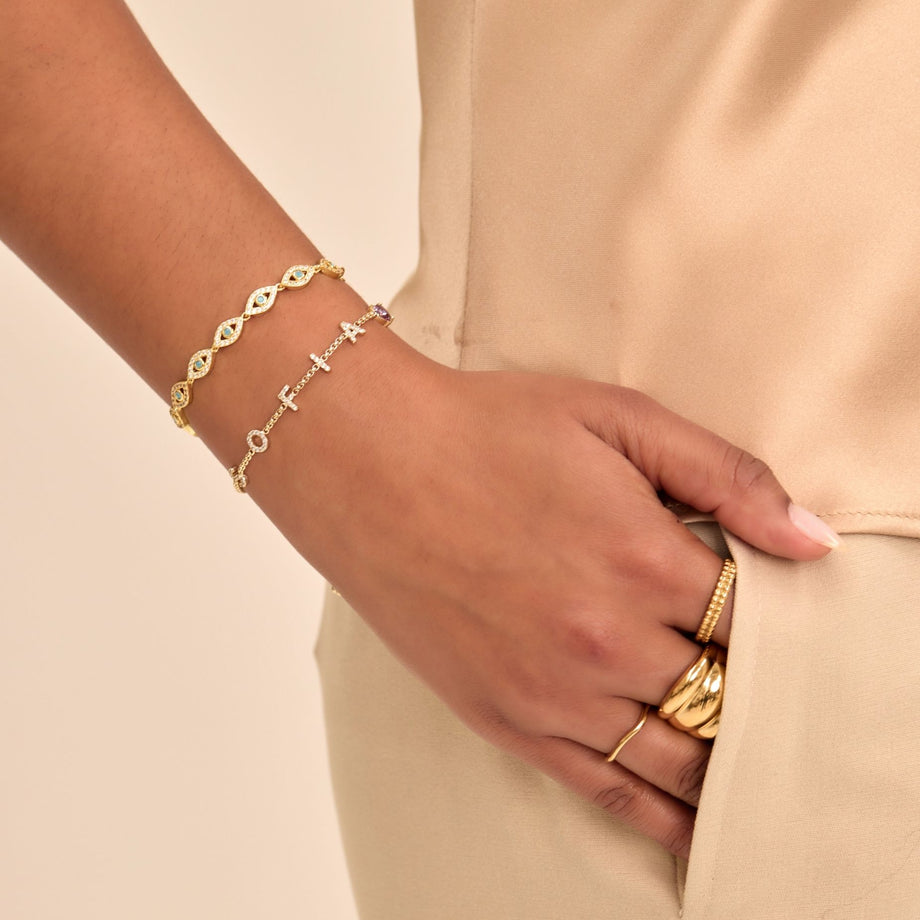 model wearing stacked bracelets, evil eye bracelet and custom name bracelet in gold from prya
