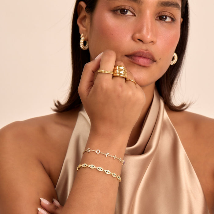 model wearing stacked bracelets, evil eye bracelet and custom name bracelet in gold from prya