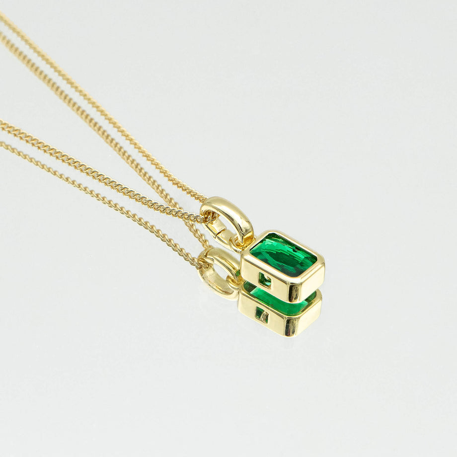 close up of emerald cut may birthstone necklace in gold from prya