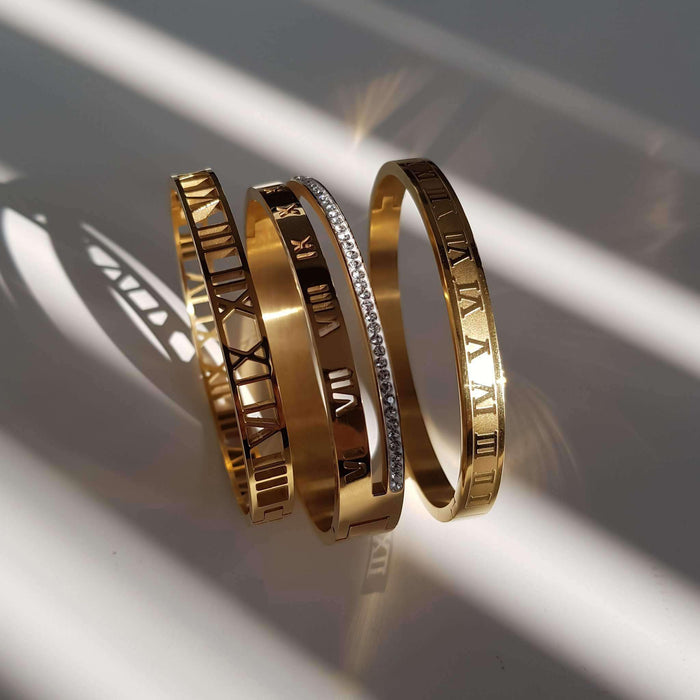 Three gold bangles with Roman numeral designs.