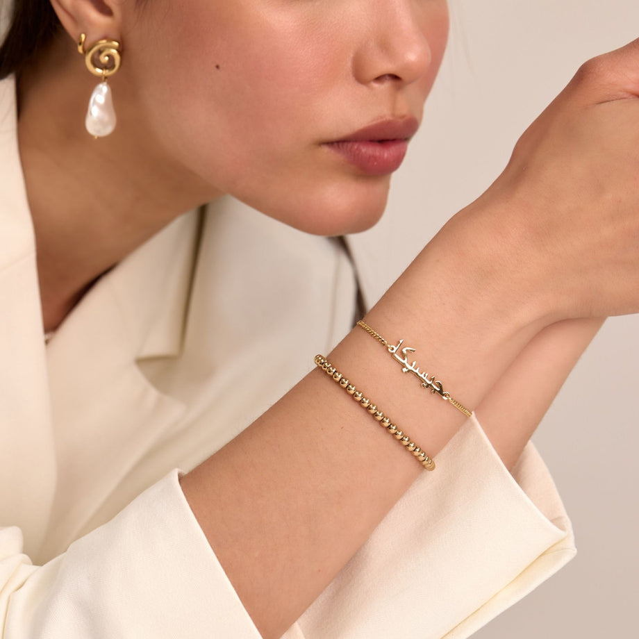 model wearing arabic name bracelet and lena sphere beaded bracelet in gold from prya