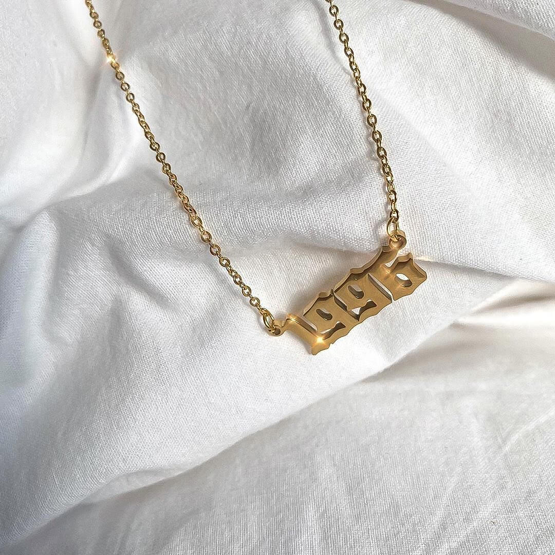  1996 birth year necklace UK in gold laid on white fabric. 