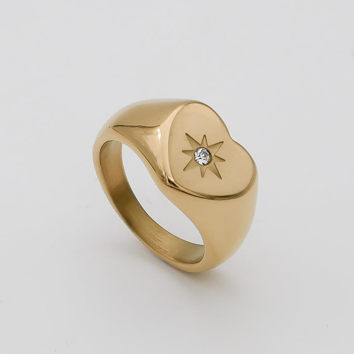 Gold heart ring with star design and gem.