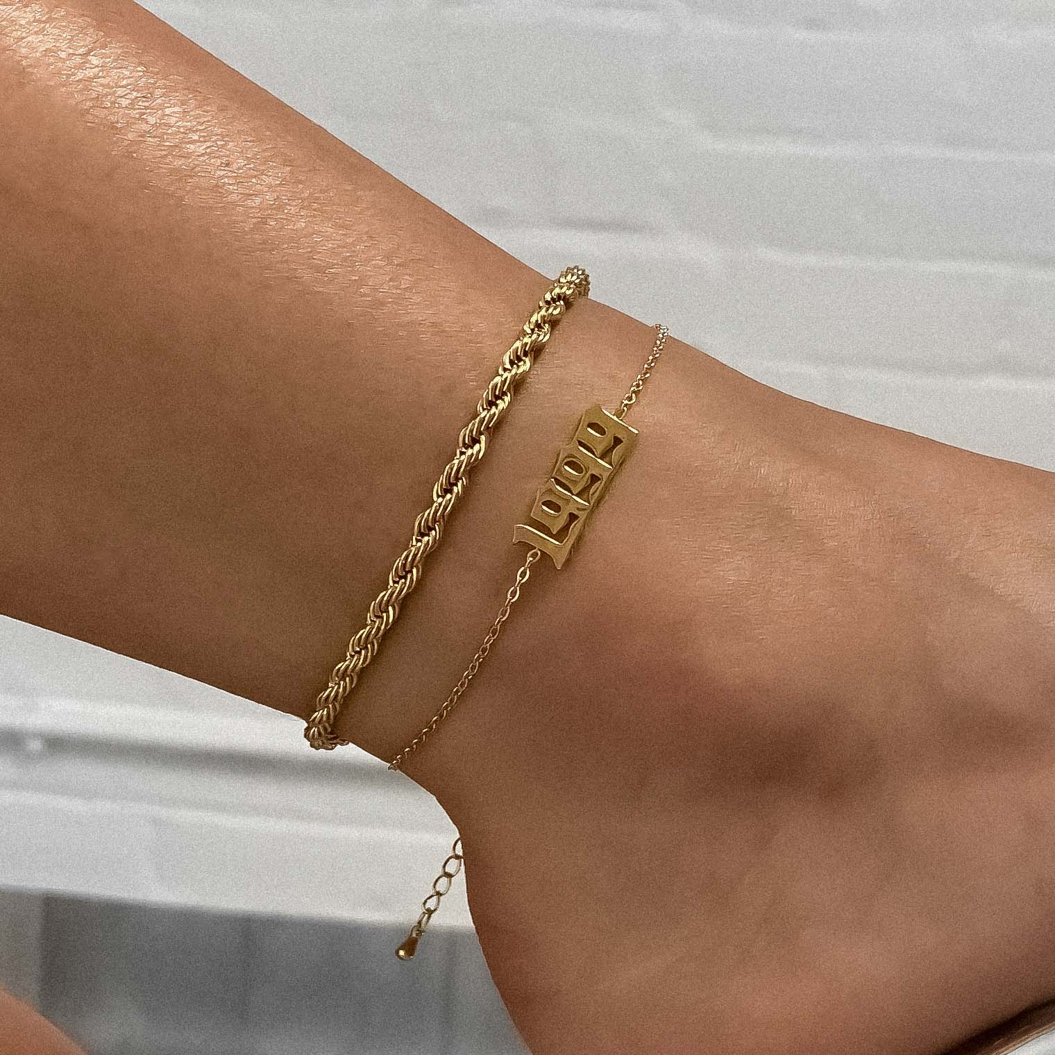Woman’s ankle sporting a 1999 gold birth year anklet and rope chain anklet
