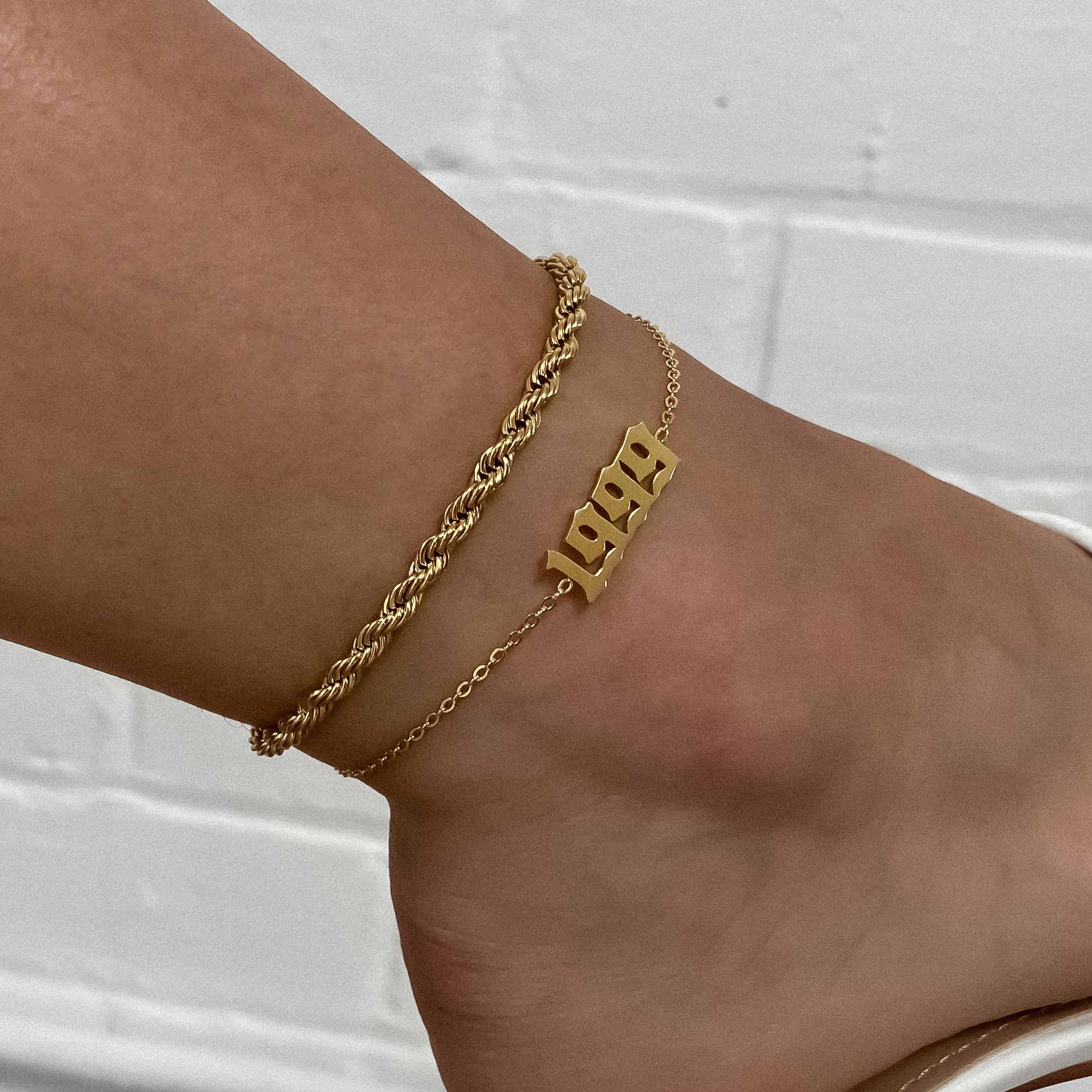 Gold birth year anklet paired with a gold twisted rope chain anklet