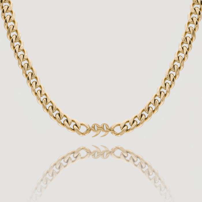 Gold chain necklace on a reflective surface.