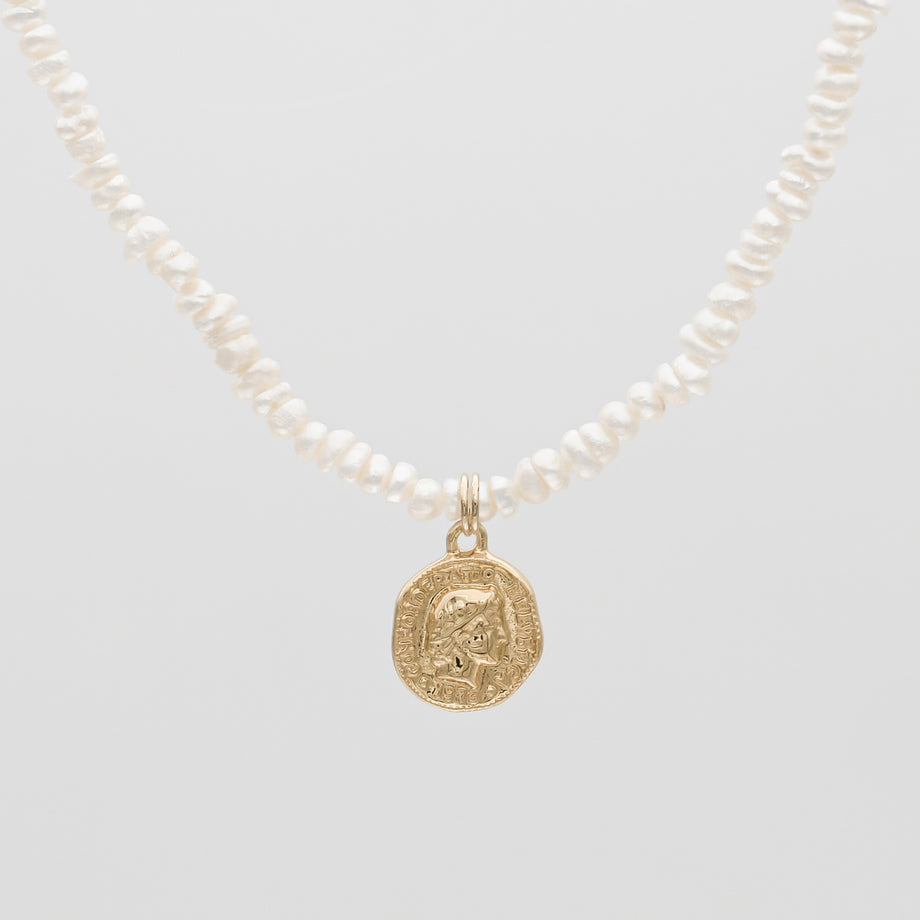 Gold coin pendant on pearl necklace.