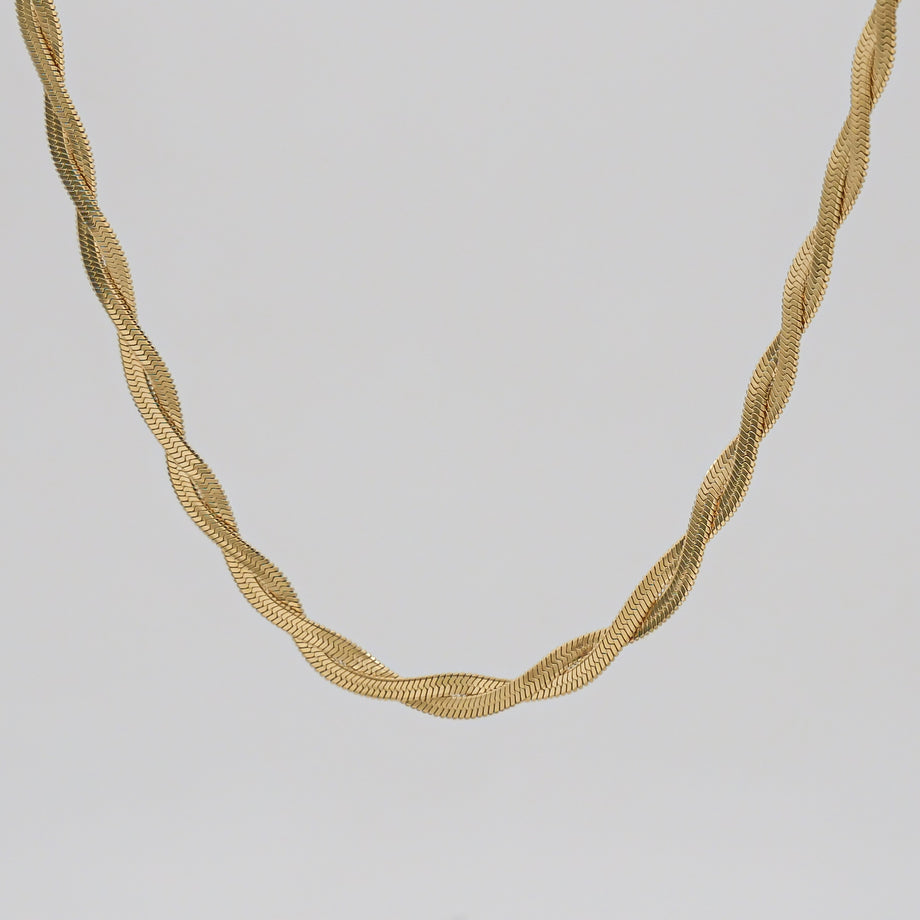 Gold herringbone necklace on white background.