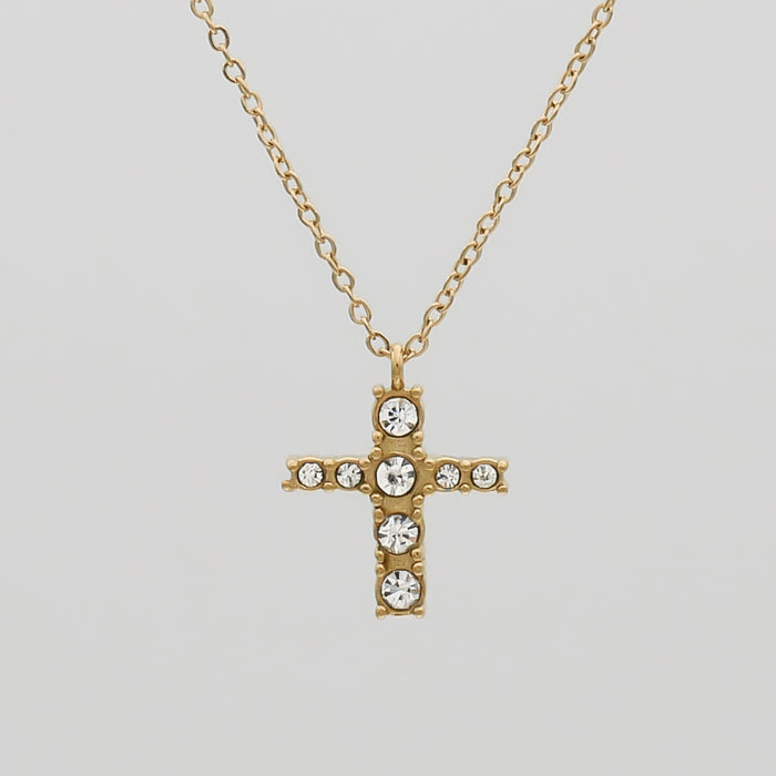 Gold cross necklace with sparkling gemstones.