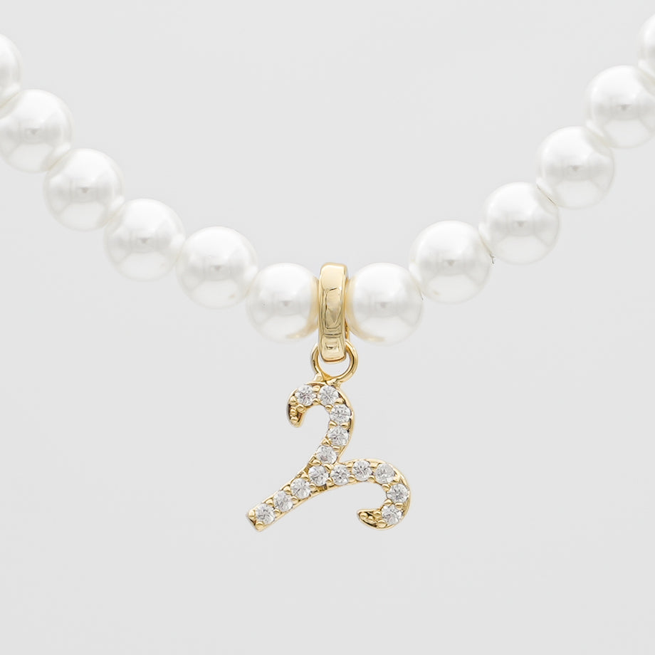 Pearl necklace with a gold zodiac charm.