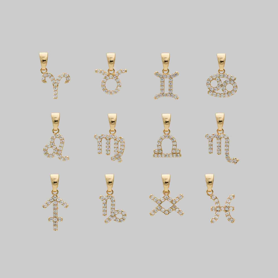 Gold zodiac symbol pendants with gemstones.