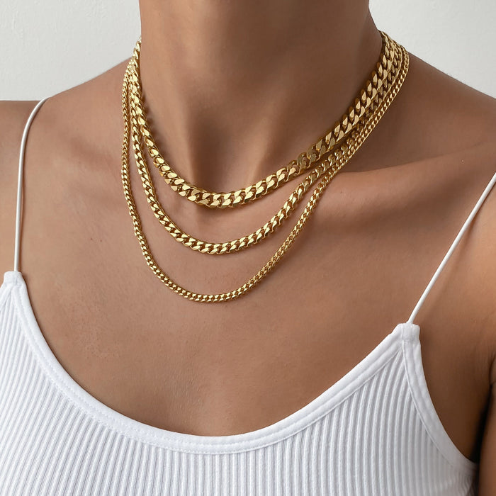 Woman wearing layered gold necklaces, white top.