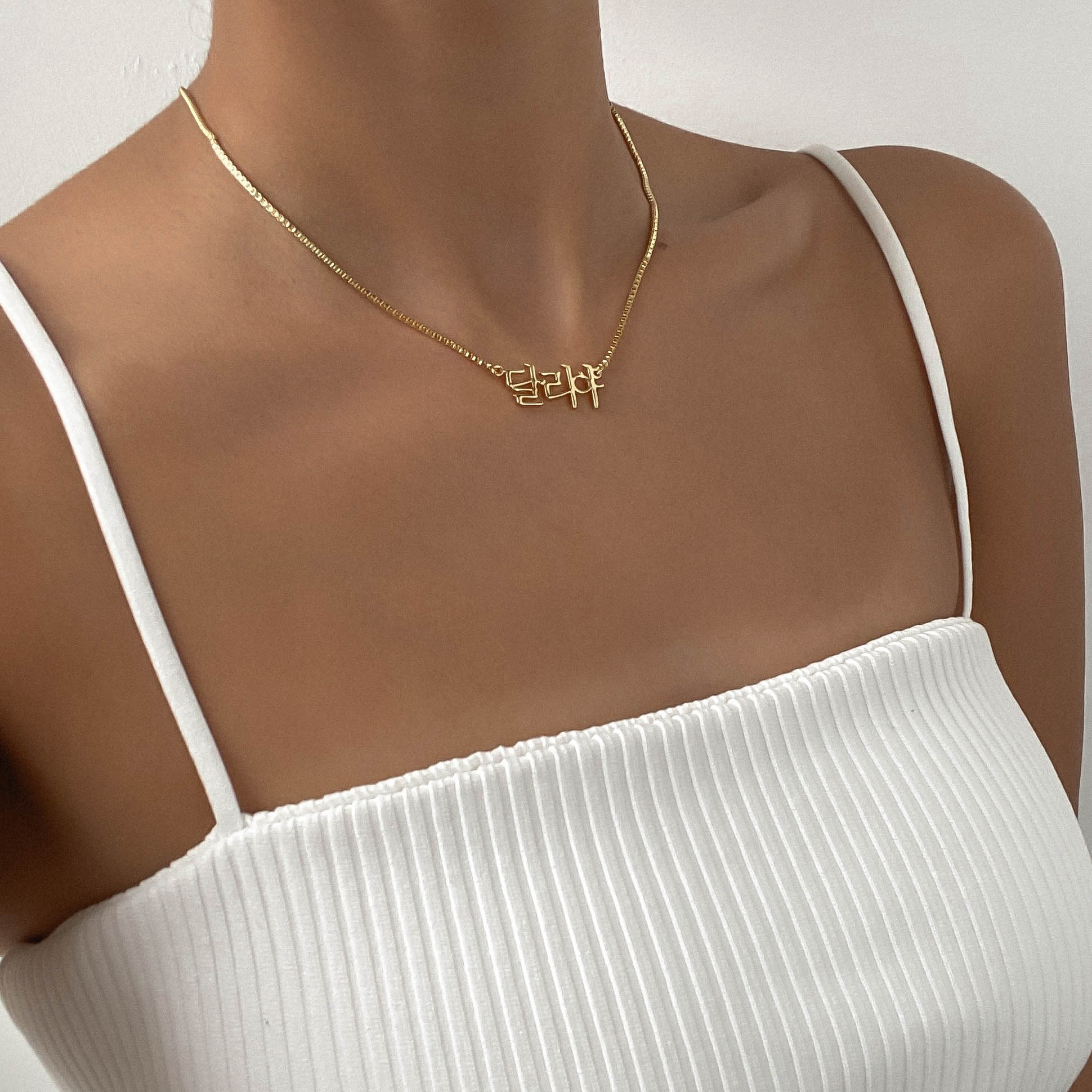 Woman wearing a white tank top with gold Korean name necklace