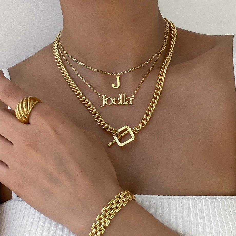 Stylish layered gold necklaces including initial and name pendants, complemented by a modern ring. Perfect for personalizing your look.