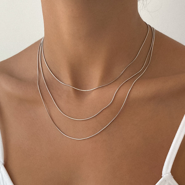 Woman wearing layered silver necklaces.