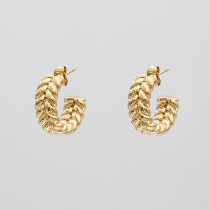 Gold twisted hoop earrings on white background.