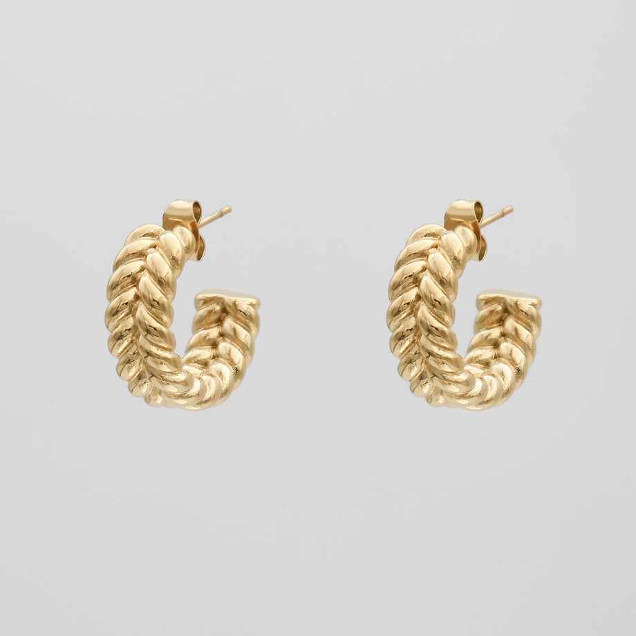 Gold twisted hoop earrings on white background.