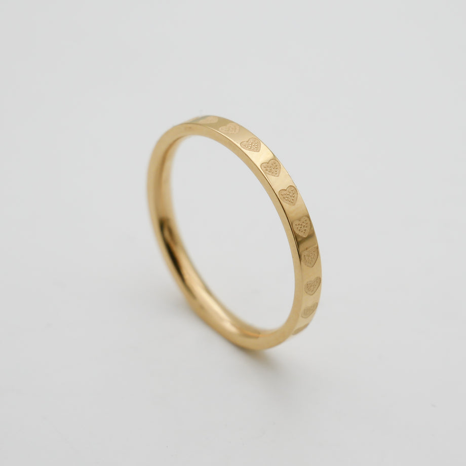 Gold ring with engraved heart pattern.