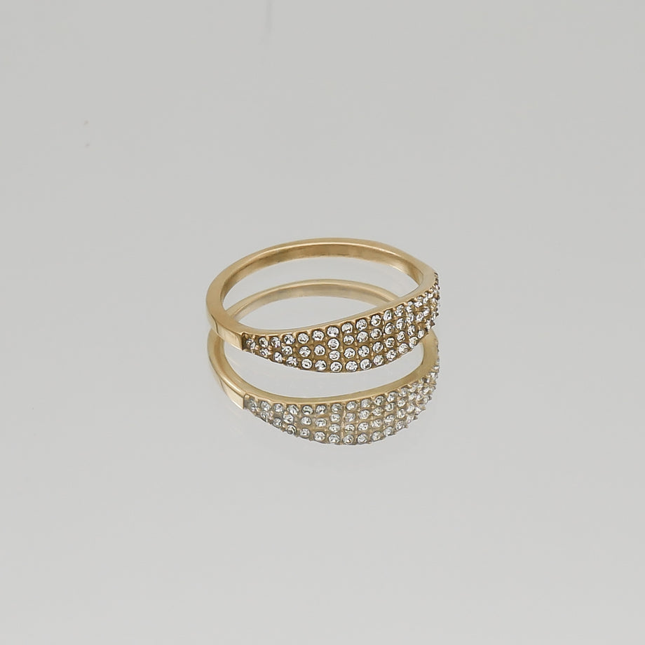 Gold ring with sparkling gemstones on reflective surface.