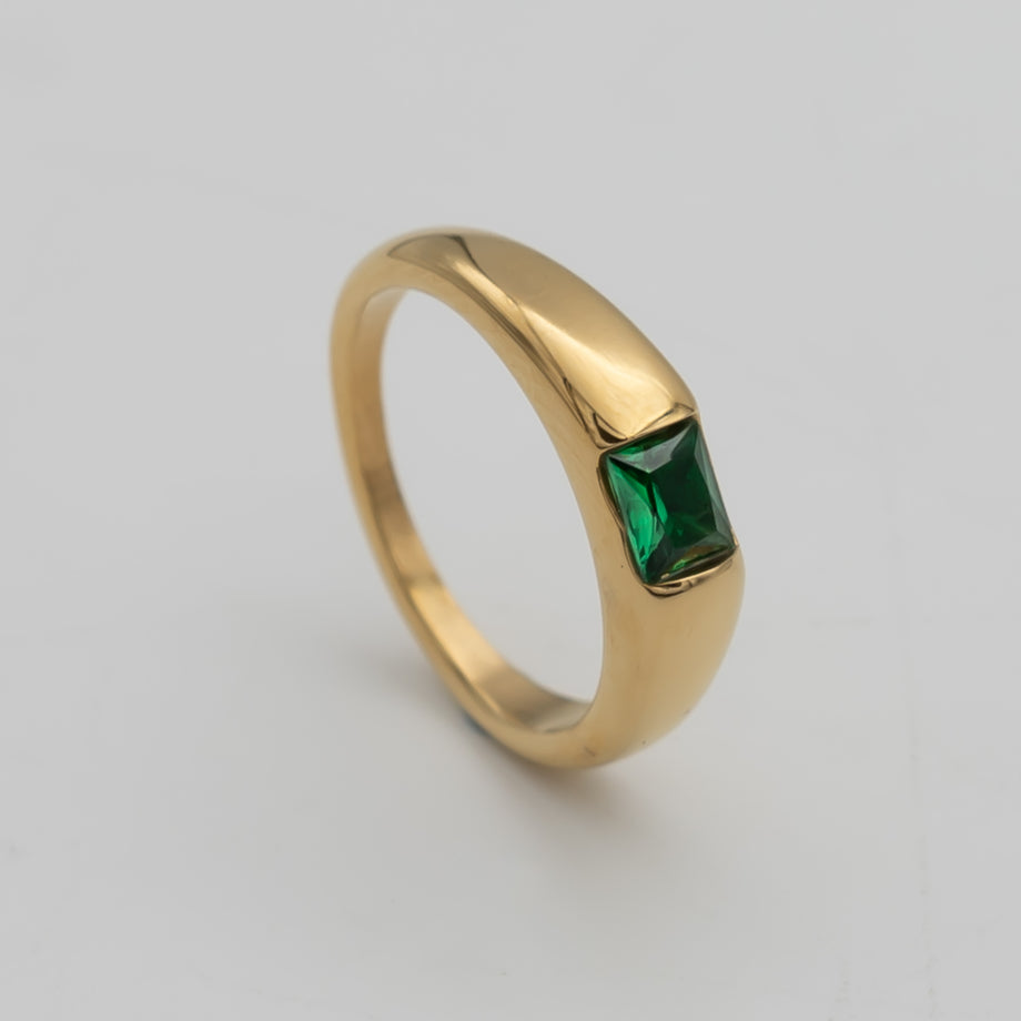 Gold ring with green square gemstone.