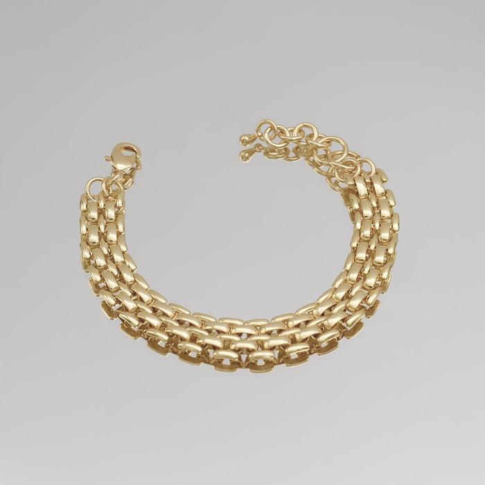 Gold chain bracelet on a grey background.