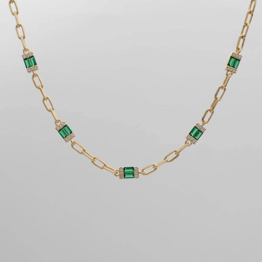 Gold chain necklace with green gemstone accents.