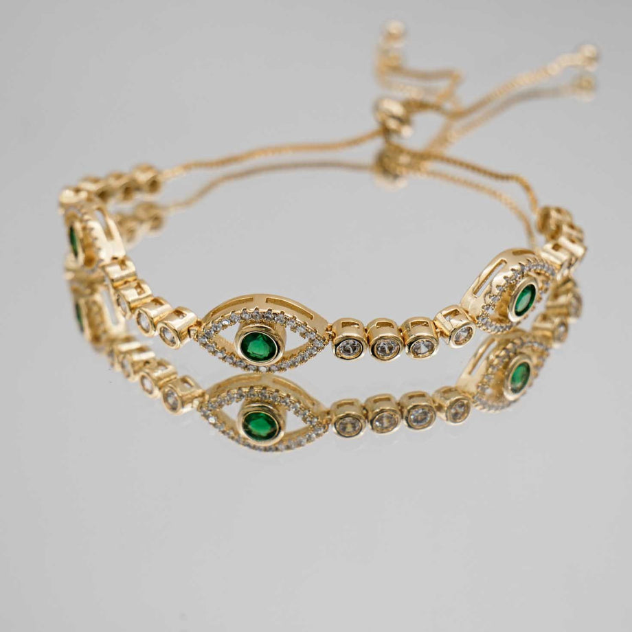 Close up of Gold Evil Suspended bracelet paved with CZ diamonds and Emerald Green Gem