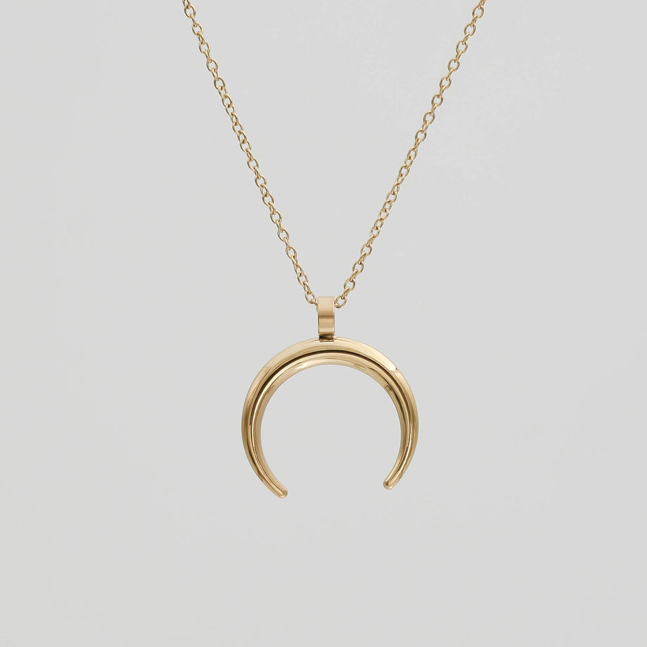 Gold crescent moon necklace on chain.