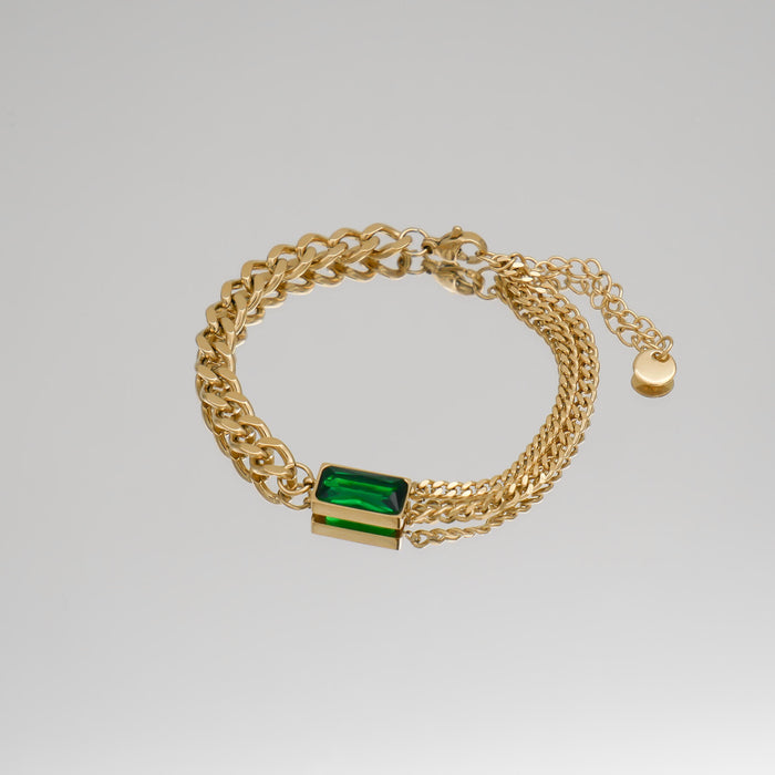 Gold bracelet with green gemstone on display.