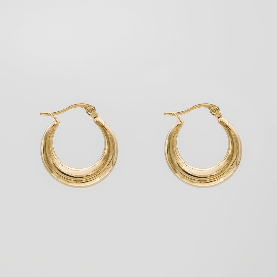 Gold hoop earrings against plain background.